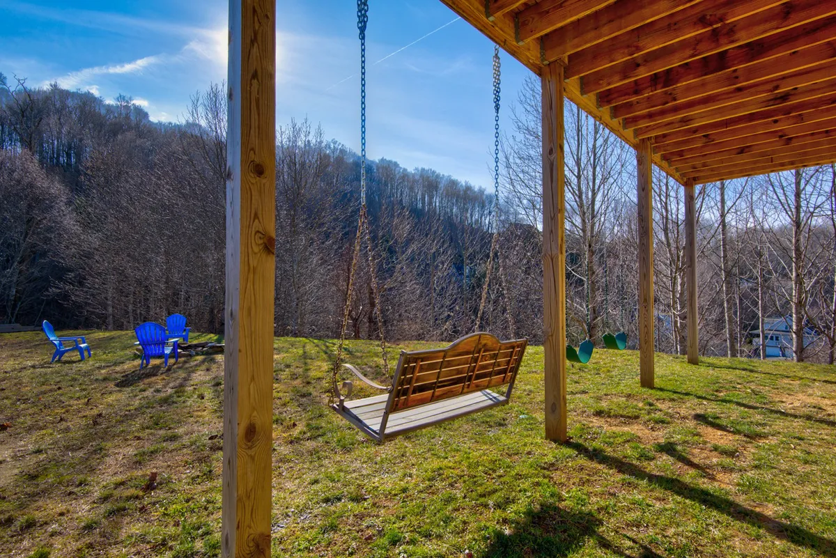 A delightful outdoor area featuring a swing and colorful blue and green chairs set against a lush natural backdrop. This playful space is perfect for kids and families to unwind, enjoy scenic views, and make lasting memories together.