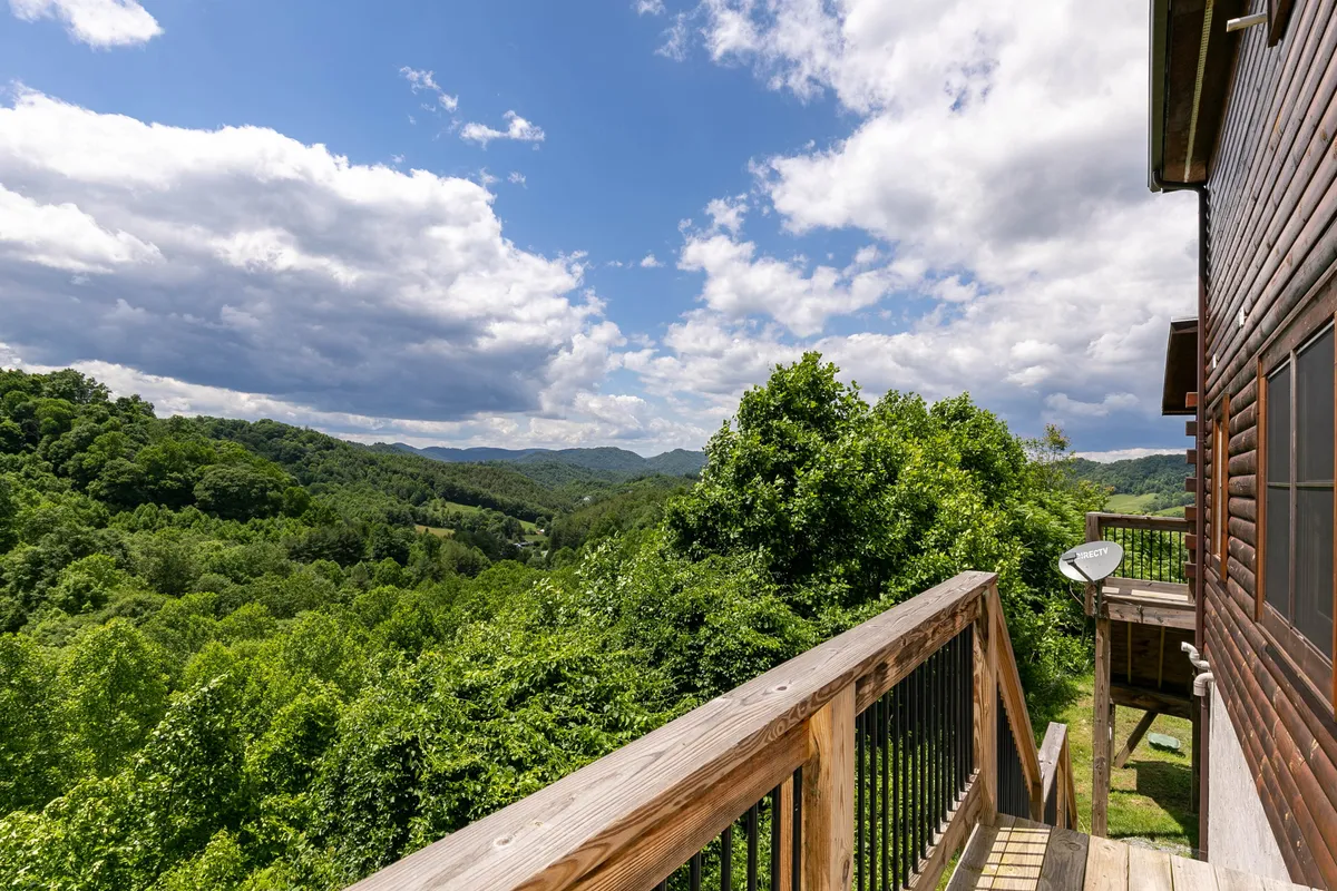 This image showcases expansive mountain views and lush greenery, as seen from a spacious wooden deck. The deck invites relaxation and provides a vantage point for soaking in nature, birdwatching, or simply admiring the dramatic landscape. The scene captures the breathtaking vistas that define North Carolina’s High Country and hints at nearby trails and forests awaiting exploration.